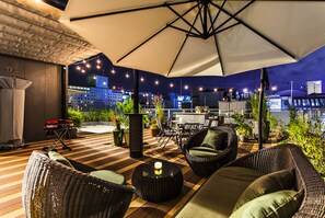 Un patio al aire libre con mobiliario de mimbre, una mesa y un gran paraguas.