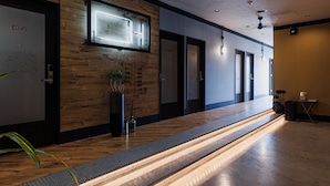 A modern hotel lobby with wooden paneling, a reception desk, and a visible elevator. - H Hotel (Fukuoka)