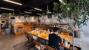 An open-plan office with multiple workstations, a reception area, and various plants. - H Hotel (Fukuoka)