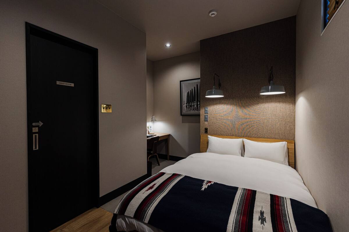 A hotel room with a bed, a desk, and a chair. There is a door labeled "Right Room" and a picture on the wall.