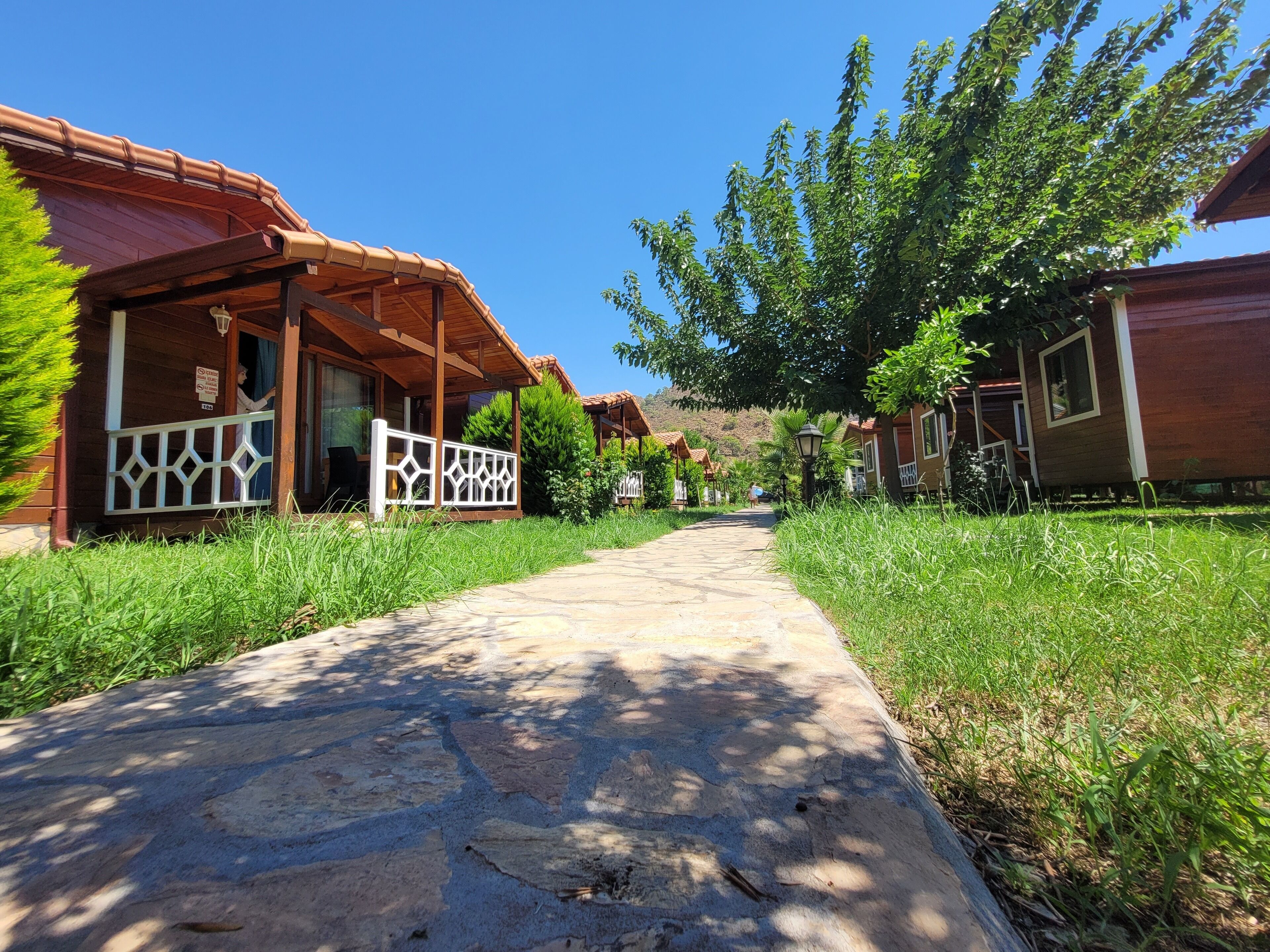 A pathway leading to wooden cabins with a covered porch and a sign indicating a smoking area.