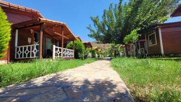 A pathway leading to wooden cabins with a covered porch and a sign indicating a smoking area.