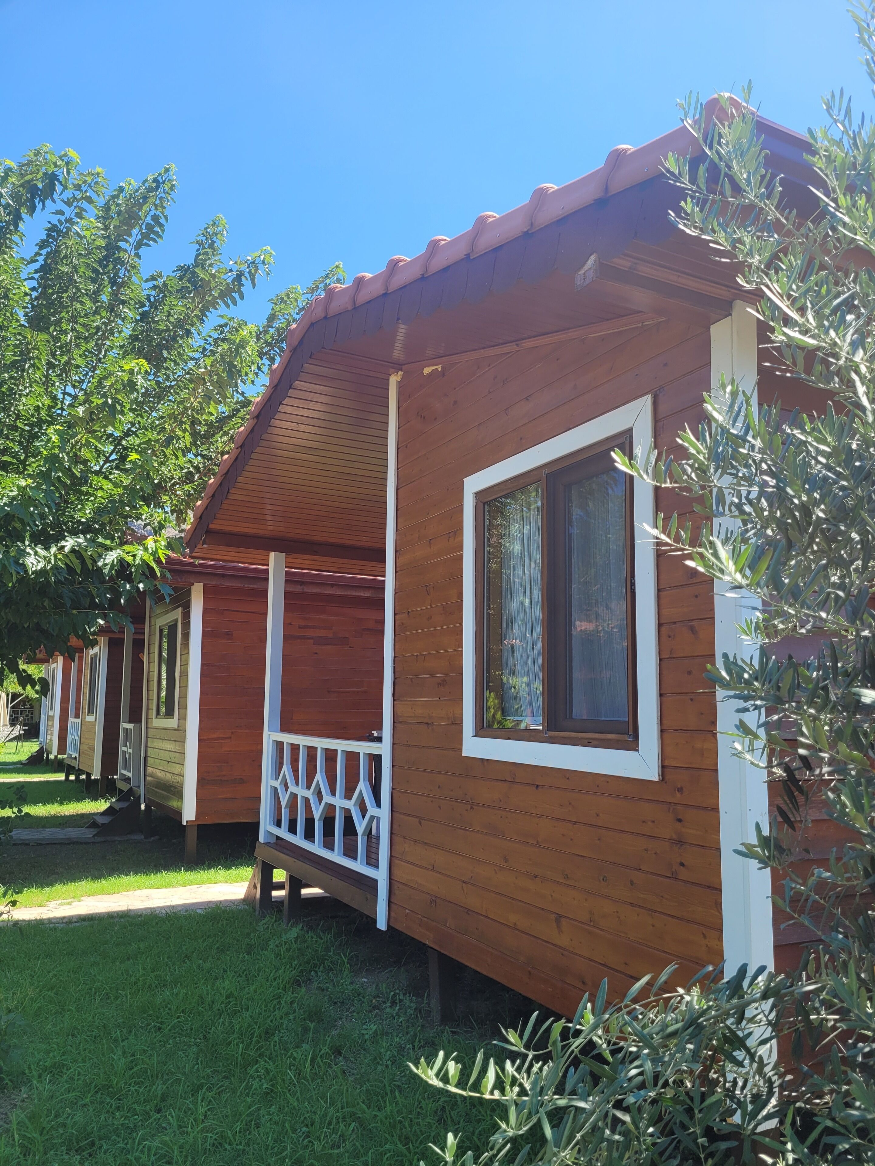 A wooden cabin with a white porch and a large window.