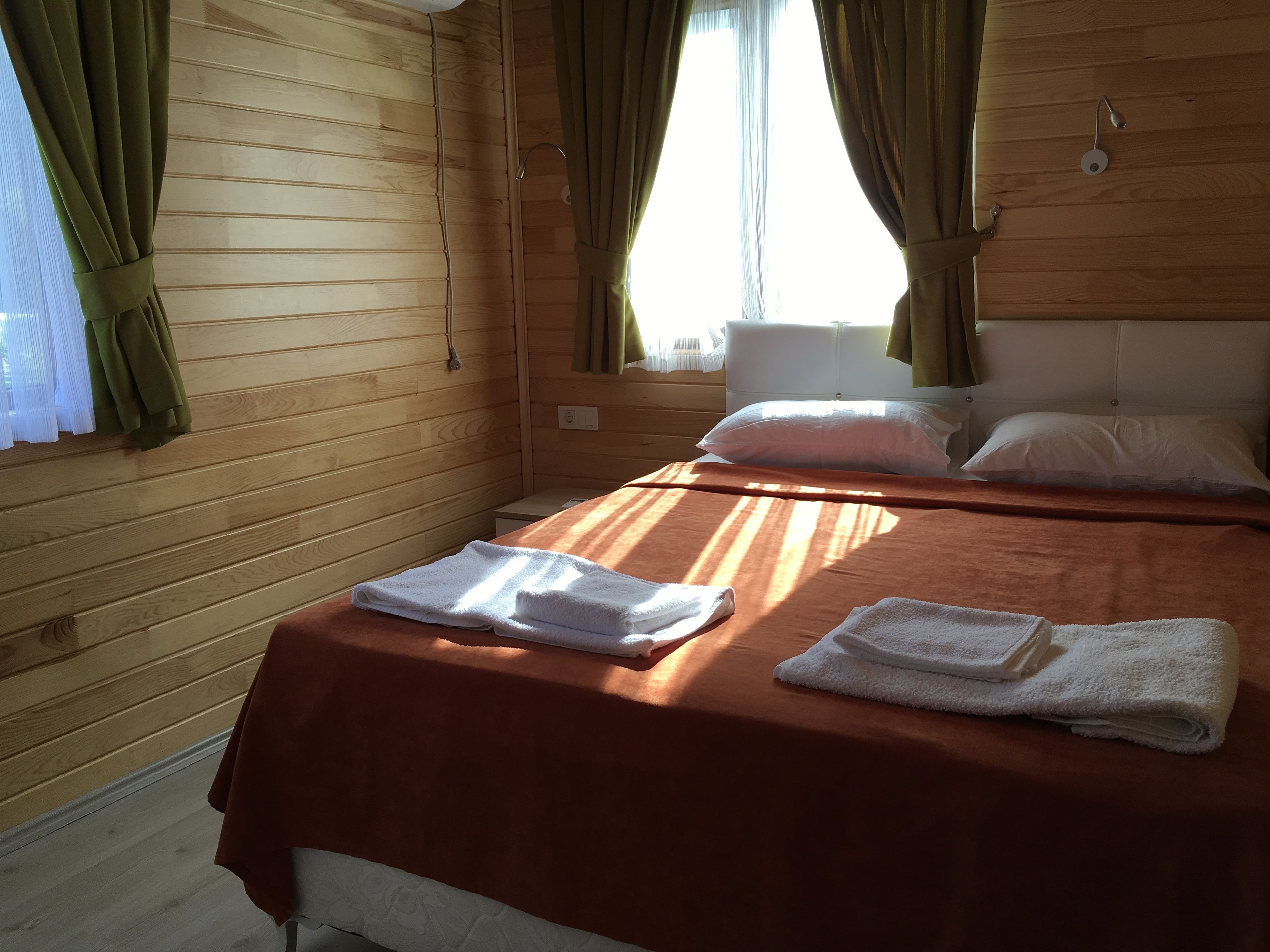 A wooden cabin room with a bed, pillows, and towels.
