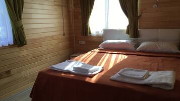 A wooden cabin room with a bed, pillows, and towels.