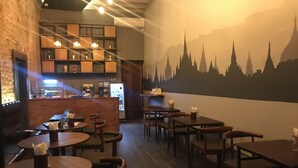 A restaurant with wooden tables and chairs, a brick wall, and a mural of a mountain skyline.
