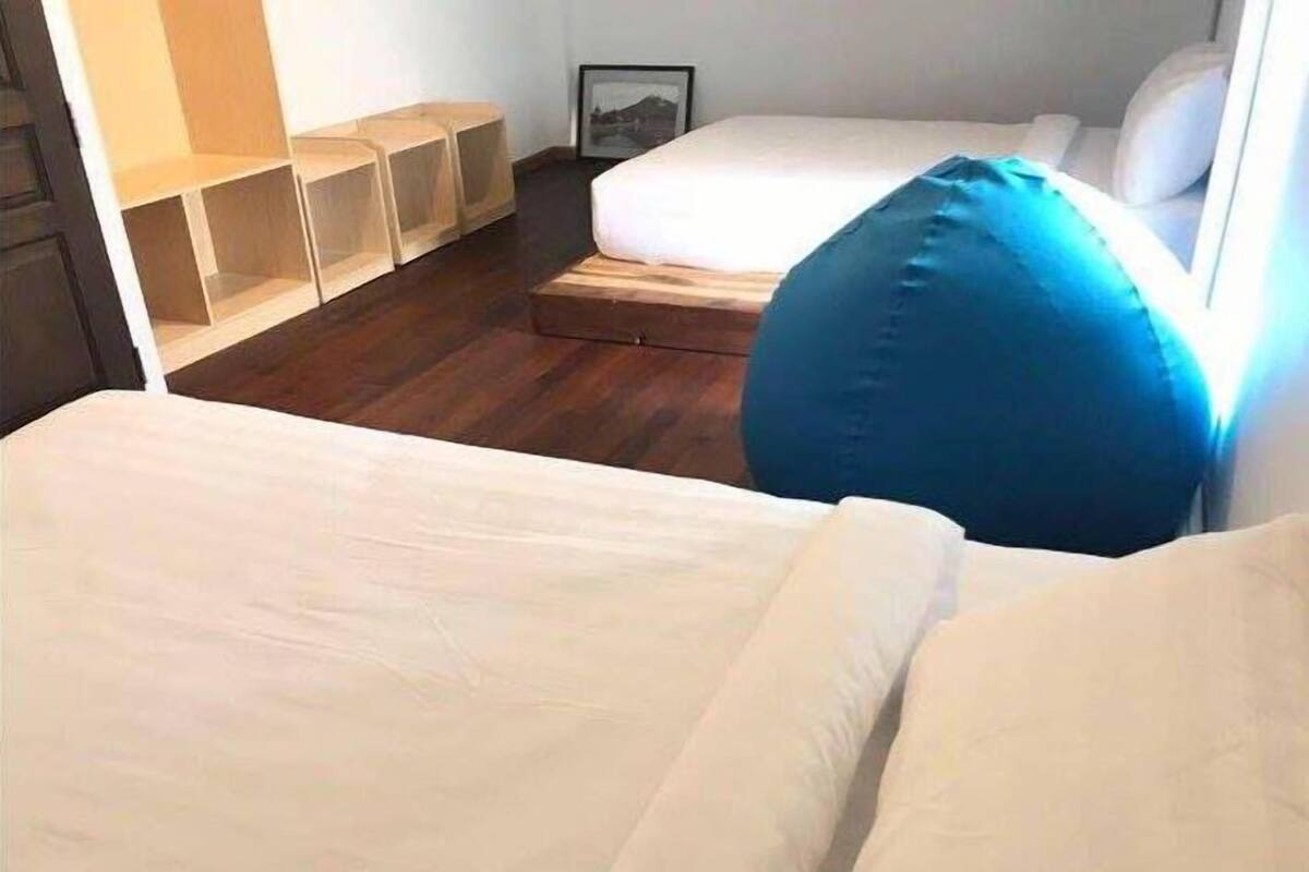 Une chambre à coucher avec un lit, un oreiller bleu et une étagère en bois.