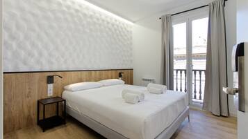 Een moderne hotelkamer met een groot bed, een nachtkastje, een wandradiator en uitzicht op het balkon.