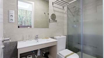 Un baño moderno con ducha de vidrio, lavamanos blanco y un inodoro.