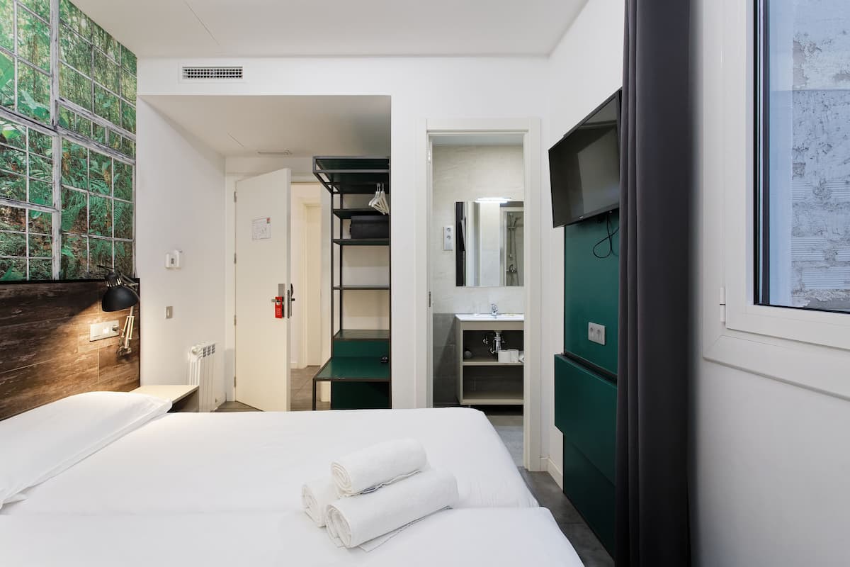 A hotel room with a bed, a wardrobe, a bathroom with a mirror, and a green wall.
