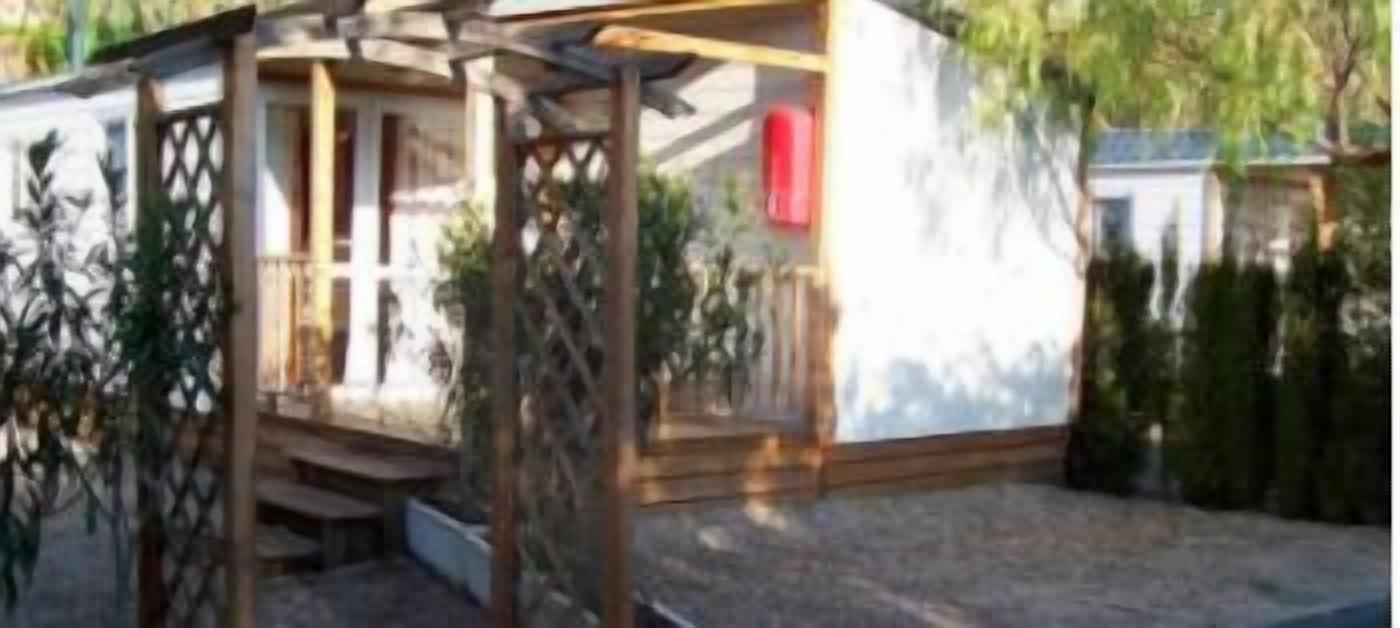 A wooden pergola structure with a covered seating area, surrounded by a garden with various plants.