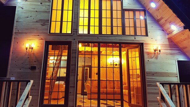 A two-story wooden cabin with large windows and a balcony.
