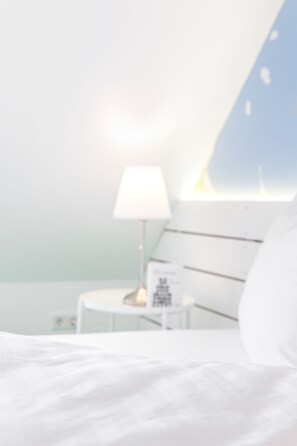 A bedroom with a bed, a bedside table with a lamp, and a window with a view. - Flowers Hotel Münster (Münster)