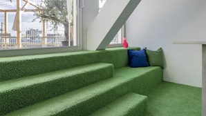 Un interior moderno con una escalera que lleva a un balcón, un ventanal y vistas al exterior.