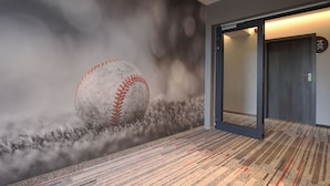 Un pasillo con un mural de béisbol, piso alfombrado y una puerta con la leyenda '304'.