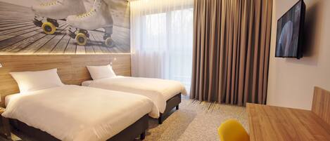 Habitación de hotel con dos camas, cabecera de madera, televisor grande y ventana con cortinas.