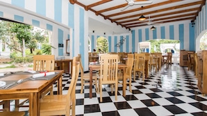 Un restaurante con mesas y sillas de madera, suelo a cuadros y paredes con franjas azules y blancas.
