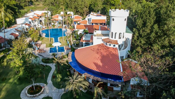 Un resort con varias construcciones, una piscina y una torre.