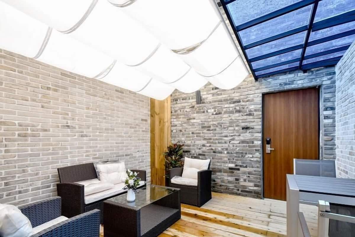 A modern outdoor seating area with wicker furniture and a glass ceiling.