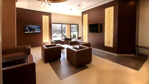 En moderne lobby med sofaer, et fjernsyn og dekorative paneler.