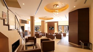 En moderne lobby med trappe, siddeområde og et stort skærmbillede.