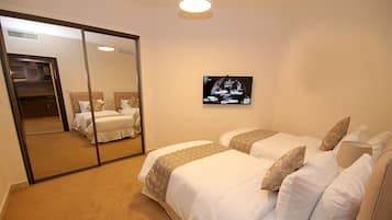 A hotel room with two beds, a large mirror, and a flat-screen TV on the wall.