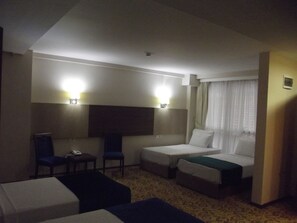 Ein Hotelzimmer mit zwei Einzelbetten, einem kleinen Schreibtisch, einem Stuhl und einem Fernseher.