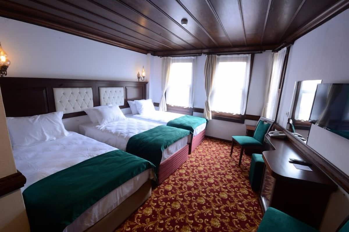 A hotel room with two beds, a desk, and a television.