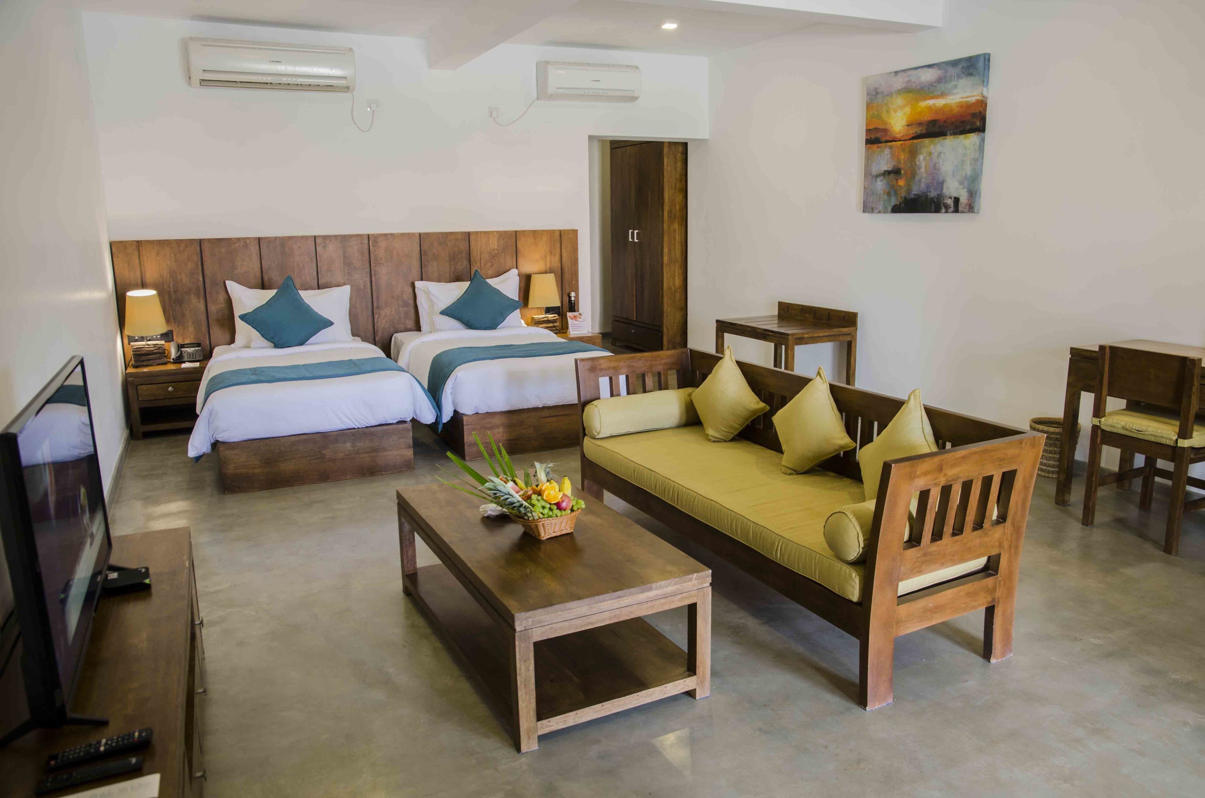 Habitación de hotel con dos camas, un sofá, un televisor y una mesa de comedor.