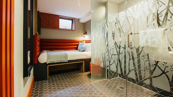 Ein modernes Schlafzimmer mit Bett, Fenster und Duschbereich mit Glastür.