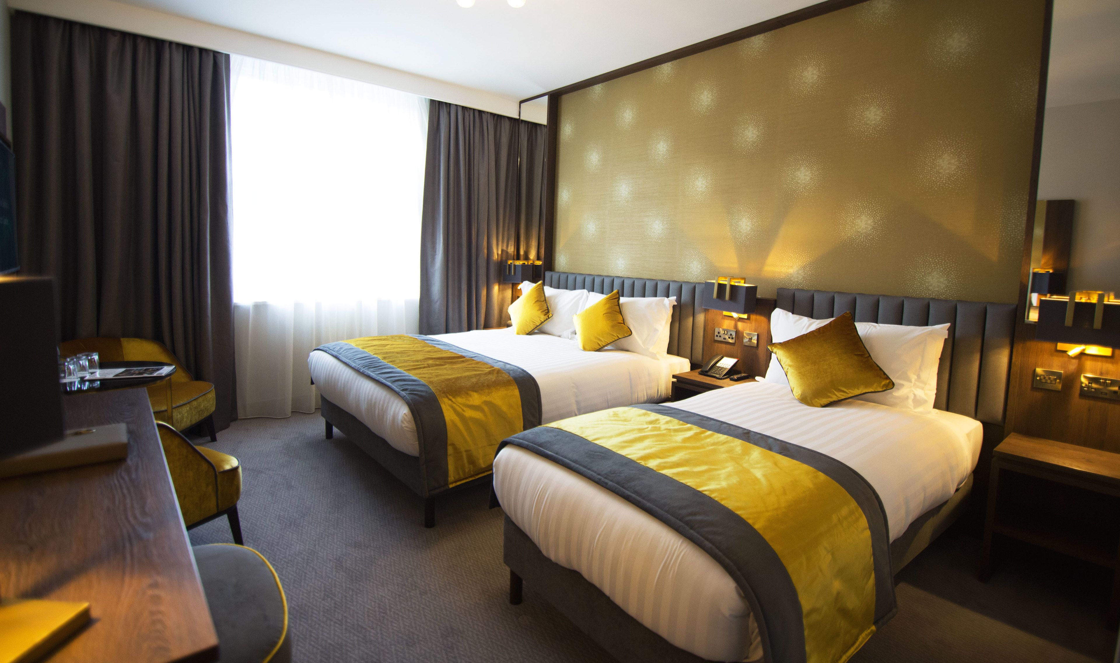 A hotel room with two beds, a desk, and a chair.