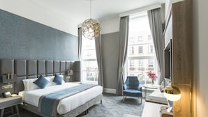 A hotel room with a large bed, a desk, a chair, and a window with curtains. - Iveagh Garden Hotel (Dublin)