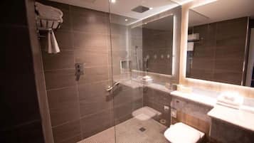 A modern bathroom with a glass-enclosed shower, a toilet, and a vanity with a mirror.