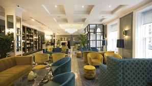 A spacious lobby with a mix of seating options, a fireplace, and a large window providing natural light. - Iveagh Garden Hotel (Dublin)