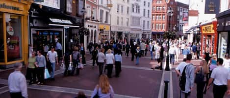 A busy street with pedestrians, shops, and historical buildings.