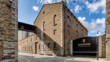 En historisk byggnad med en fasad av sten, en stor svart port med Guinness-logotypen och en kullerstensgata.