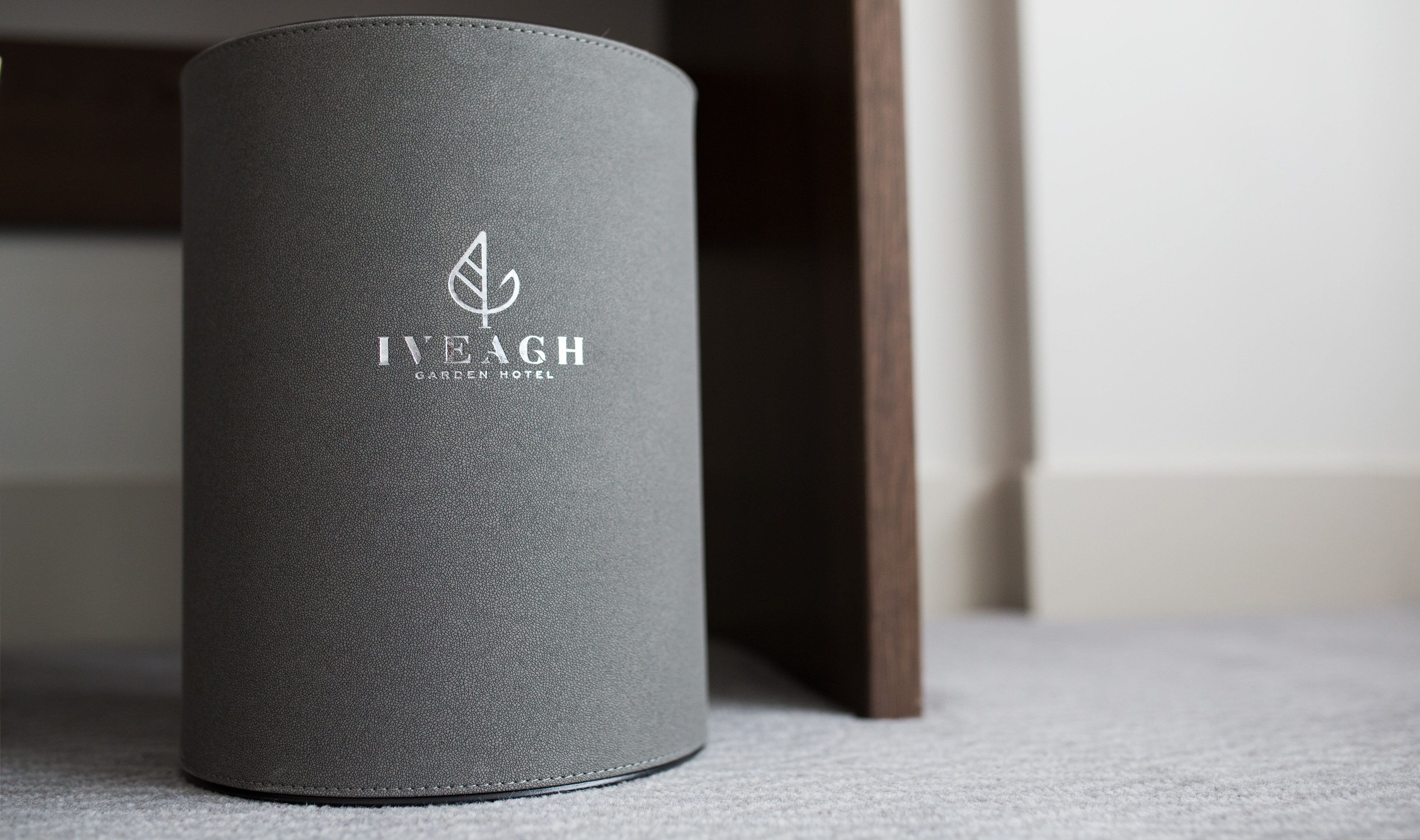 Objecte cilíndric i texturat amb un logotip i la frase “IVEAGH GARDEN HOTEL” sobre un sòl amb moqueta.