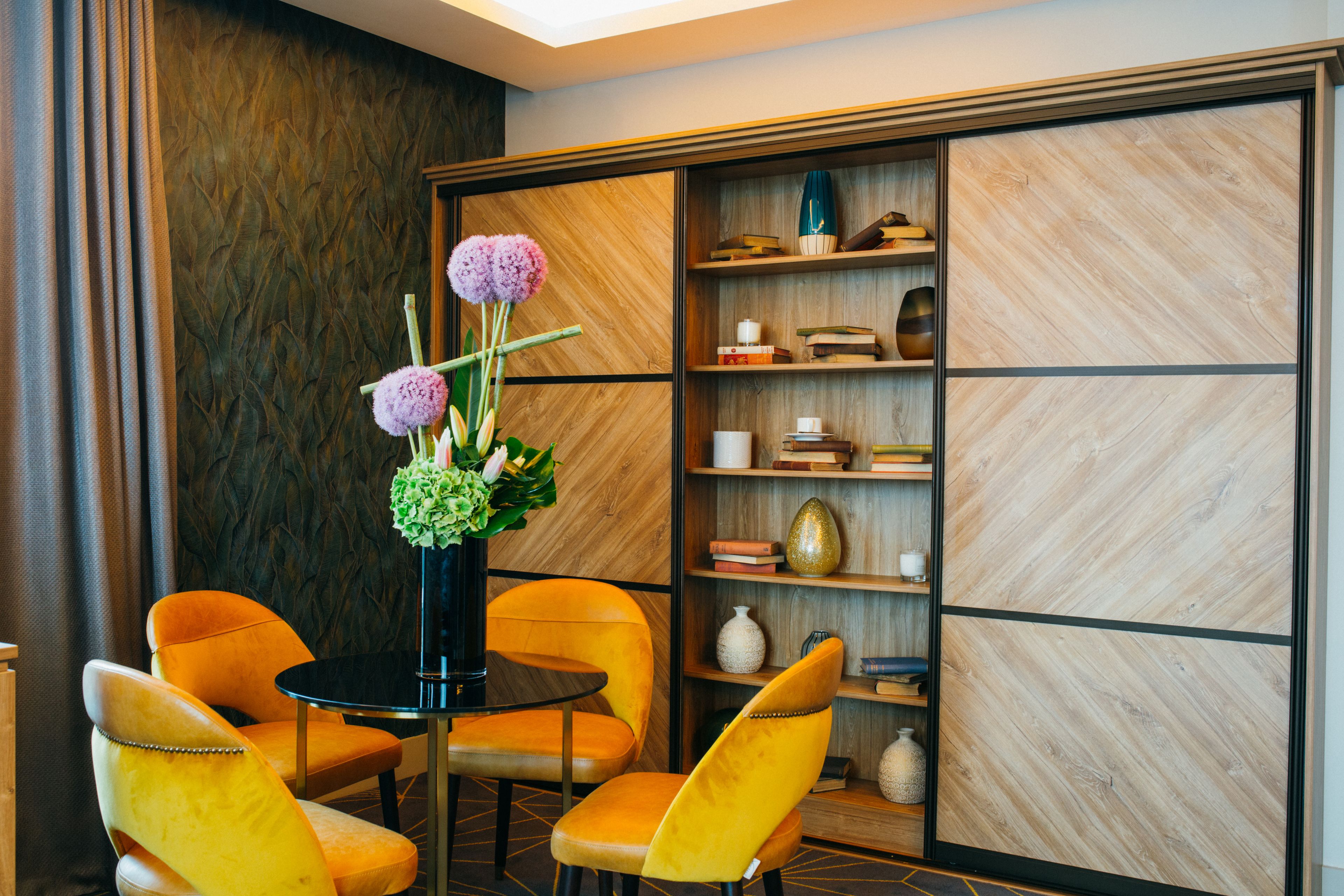 Une pièce moderne avec deux chaises jaunes, une table noire et un vase décoratif contenant des fleurs.