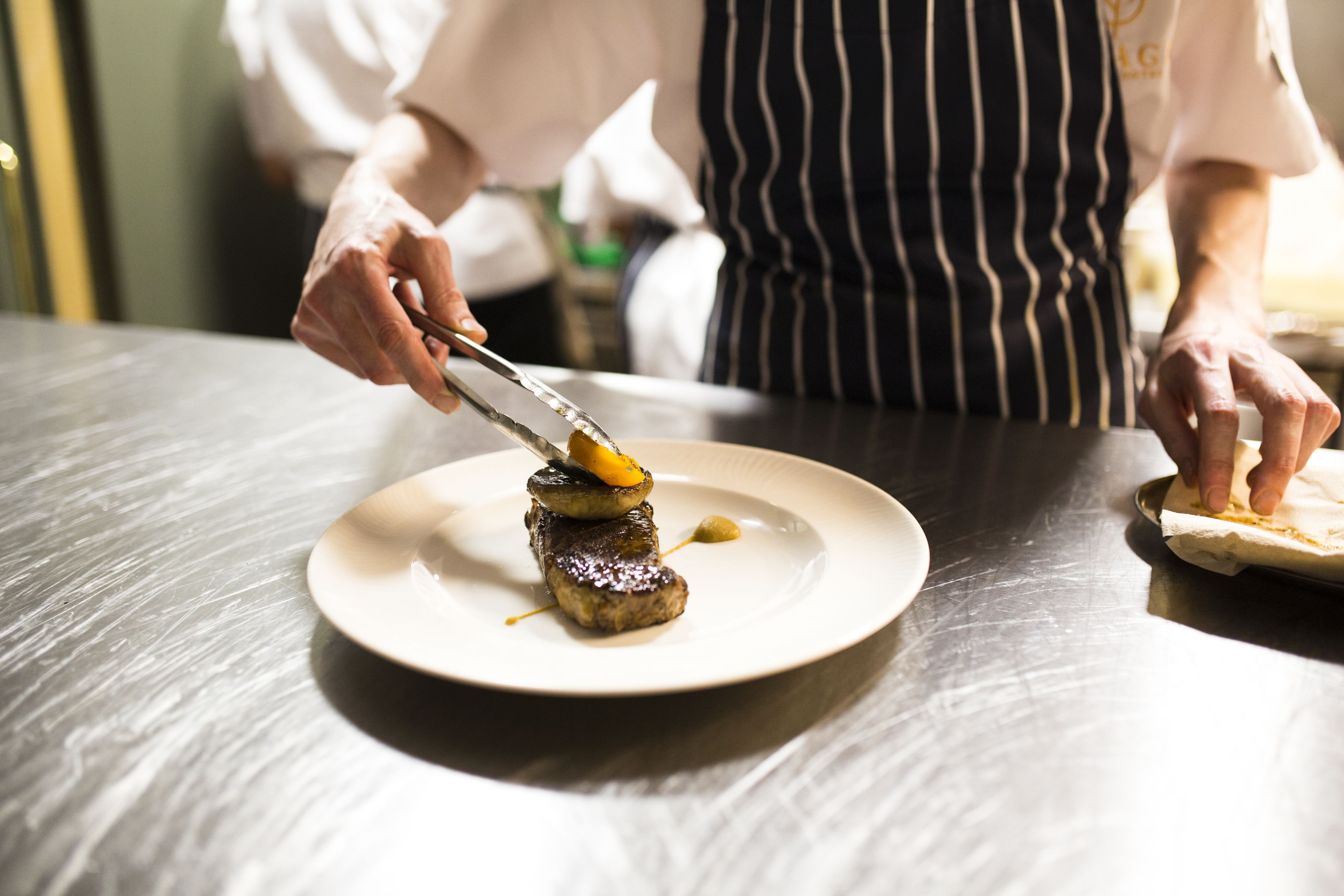A chef preparing food on a plate.