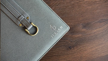 Un carnet à couverture en cuir, doté d’une fermeture métallique et d’un texte en relief.