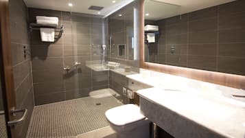 Een moderne badkamer met een glazen douchecabine, een toilet en een wastafel met een grote spiegel.