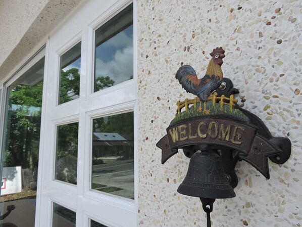 A welcome sign with a rooster on a wall.