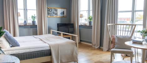 Una habitación de hotel con cama, escritorio, silla y televisor.