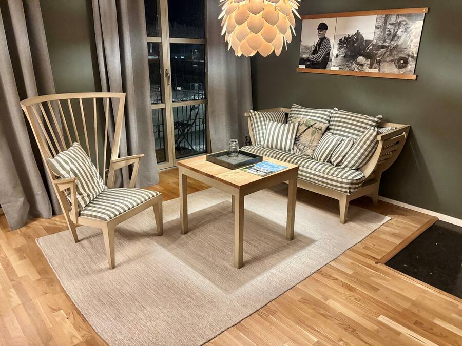 A living room with a wooden chair, a sofa, a coffee table, and a large window with curtains.