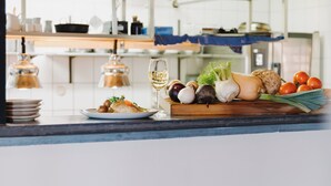Un piano di lavoro della cucina con un piatto di cibo, un bicchiere di vino e diverse verdure.