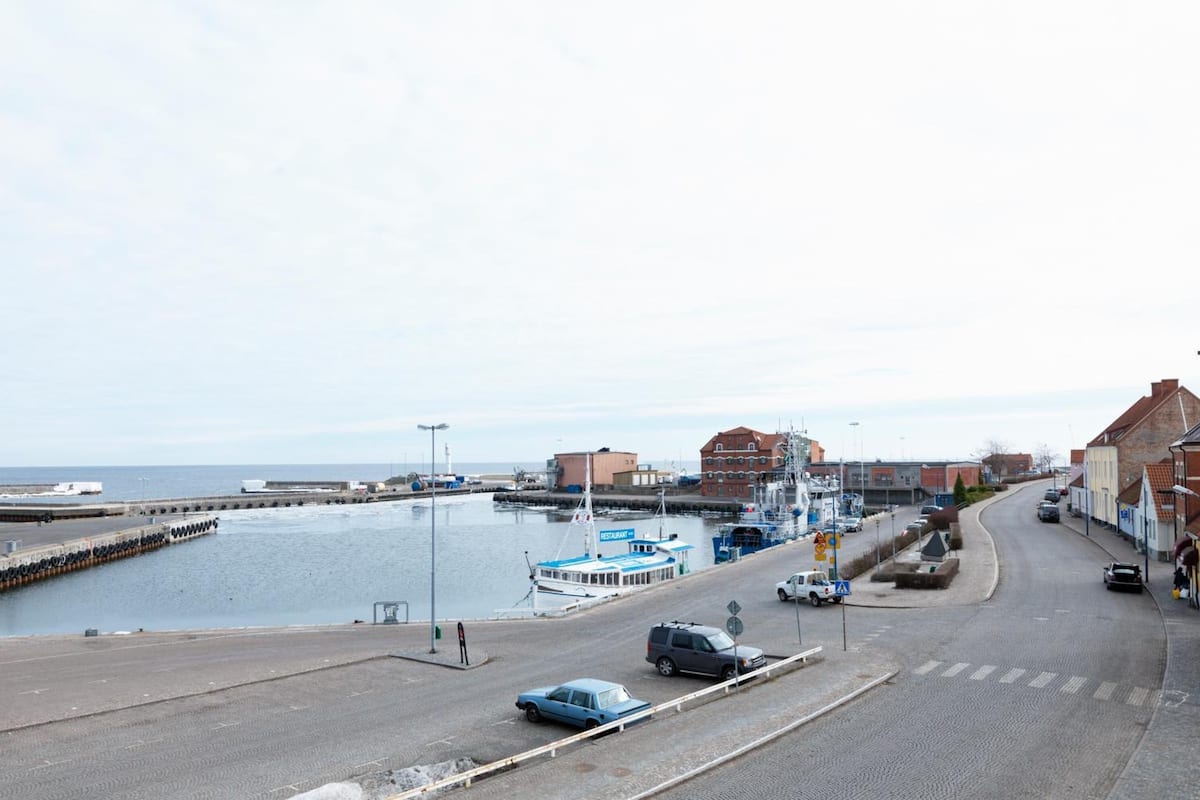 Eine Küstenstraße mit einem Hafen, Gebäuden und blauem Himmel.