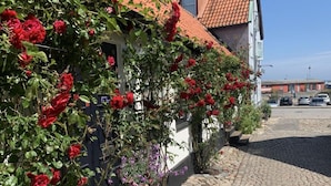 Un edificio con tetto in tegole rosse, facciata bianca e un giardino con rose rosse.