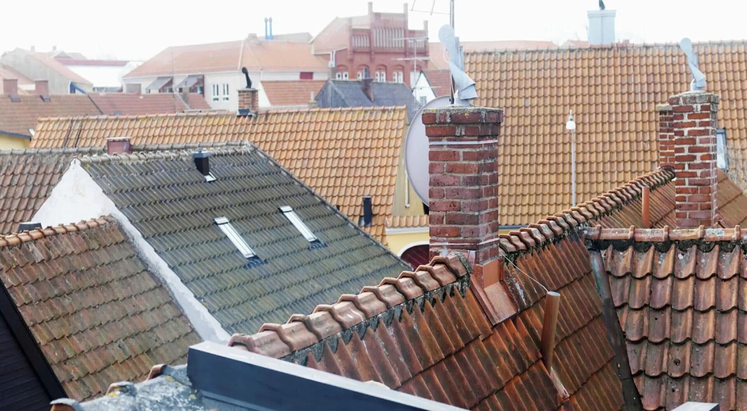 A rooftop with terracotta tiles, a chimney, and a satellite dish.