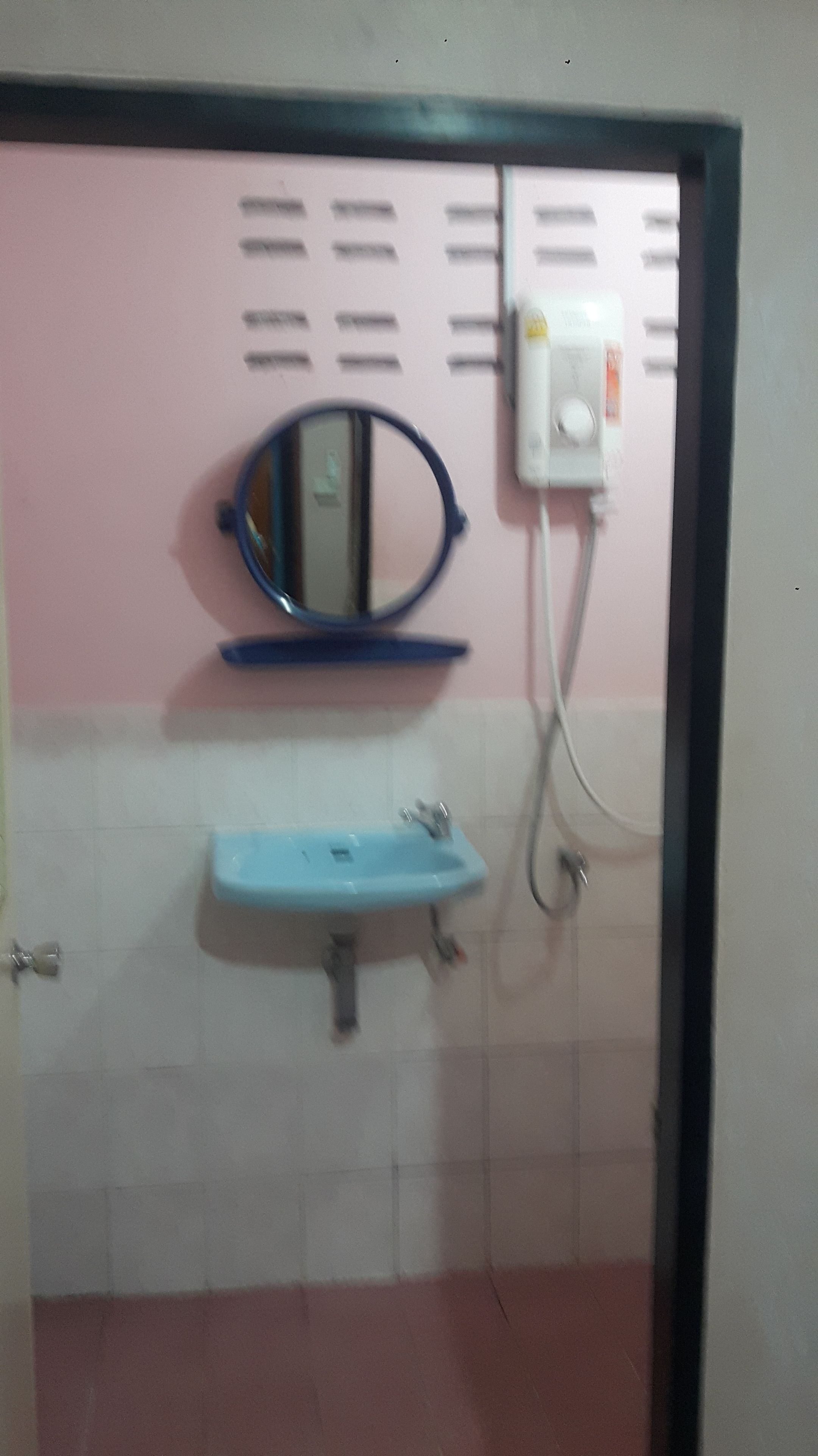 A bathroom with a blue sink, a mirror, and a white wall with a pink section.