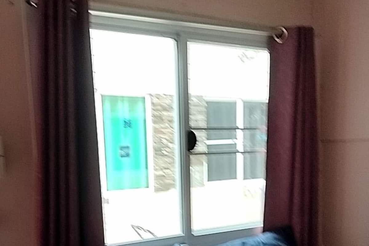A room with a bed, a window, and curtains.